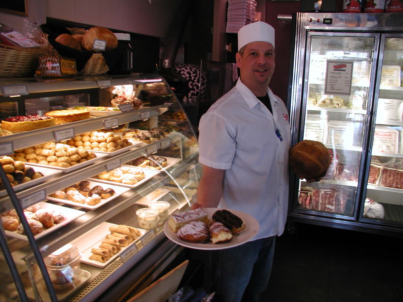 Touch of Italy's Peter Todd Scioli holds a boule of rustic Italian bread and presents a tray of enticing pastries. To meet an ever-growing demand for baked goods, the business is expanding its bakery and will open a new store in the Villages of Five Points this spring. The new facility will sell to the public and sell wholesale to area restaurants. BY HENRY J. EVANS JR.